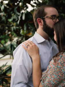 An engaged couple gets close underneath their favorite magnolia tree during their photo session.