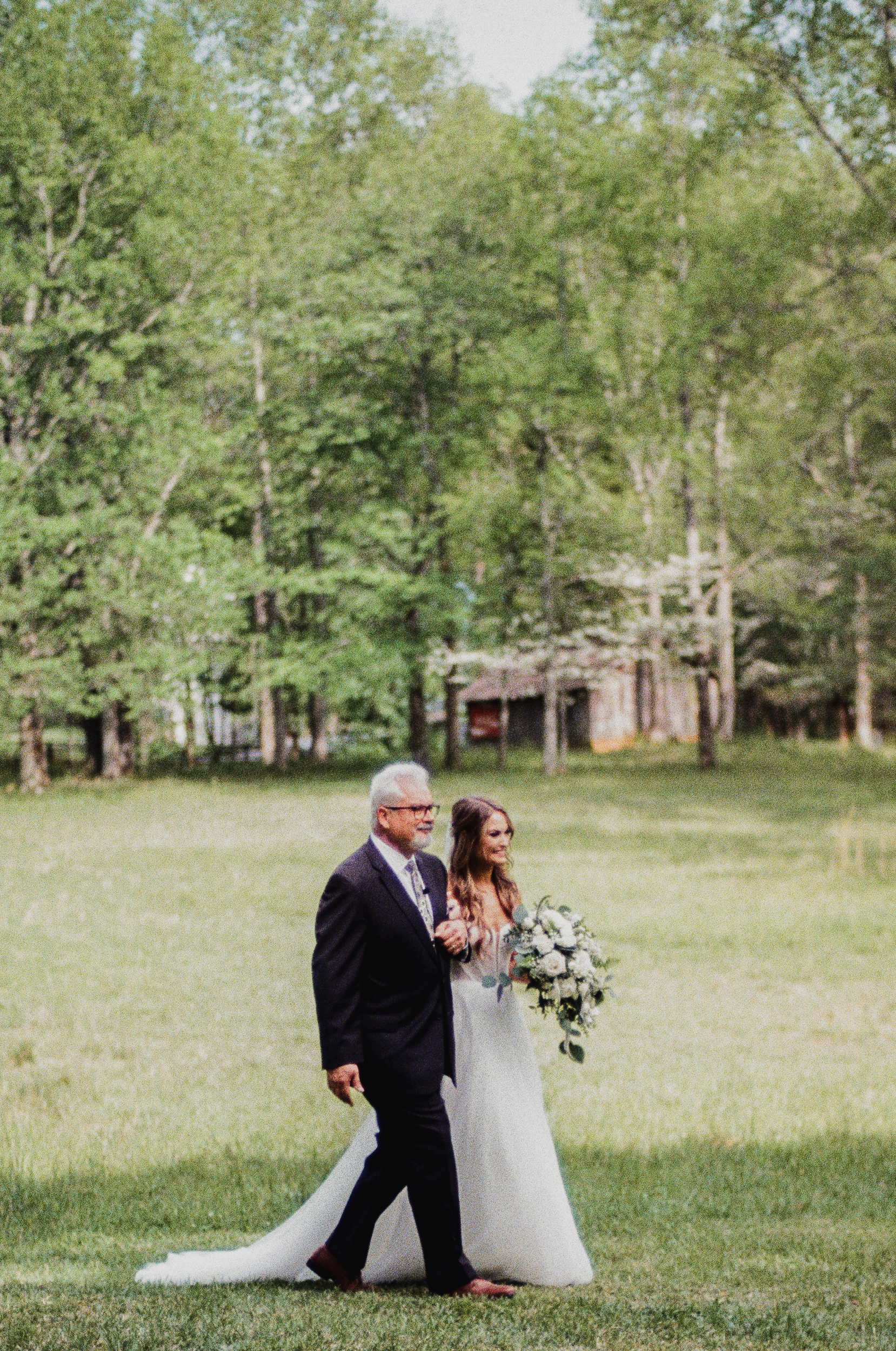 Father of the bride and bride walk down the aisle.